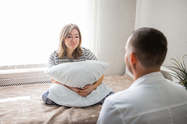 Lady sitting on bed, hugging a pillow